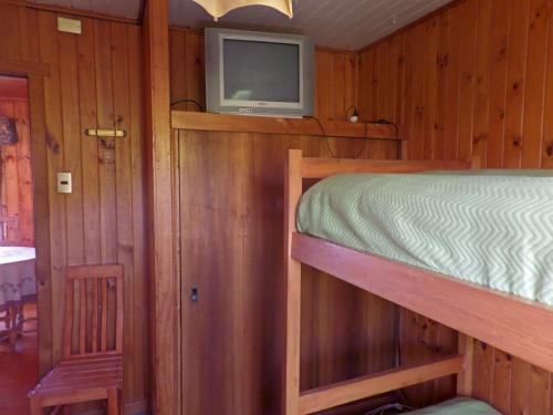 a bedroom with a bed and a tv on a wall at Hostal y Cabañas Villa Germana in Puerto Varas