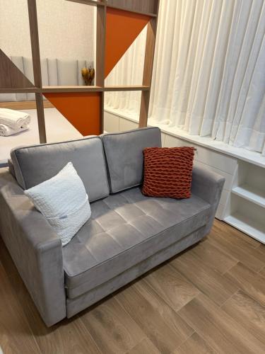 a couch with two pillows sitting in a living room at FLAT NOVO e ACONCHEGANTE in Ribeirão Preto