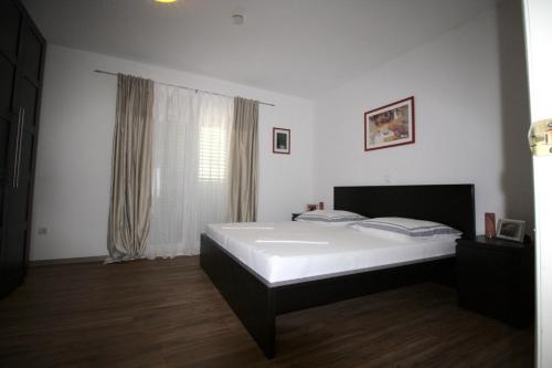 a bedroom with a bed with white sheets and a window at Apartment Dalmatien Traumhaus in Makarska