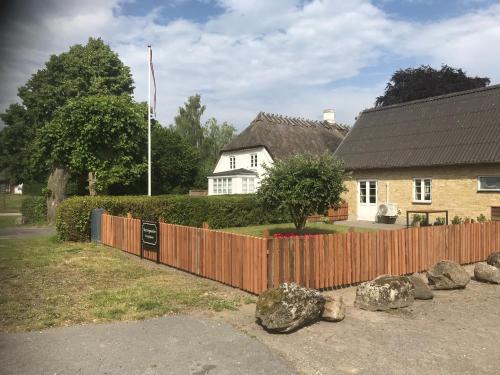 a house with a wooden fence in front of a yard at Staevnegaarden in Flødstrup