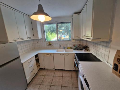 a kitchen with white cabinets and a sink and a window at Relax Dream Villa-House, Apartement, Studio in Kallithea Halkidikis