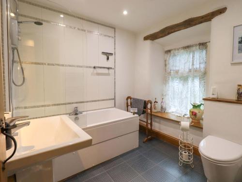 a bathroom with a tub and a sink and a toilet at Fellside Cottage in Bowness-on-Windermere