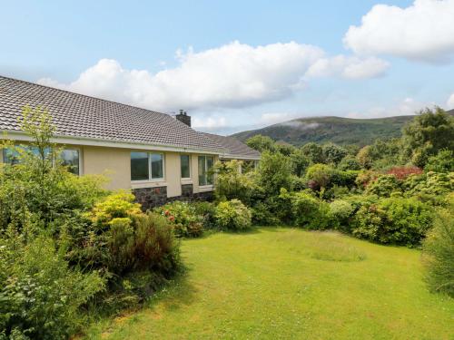 a house with a garden and mountains in the background at Knockendoch in Dumfries