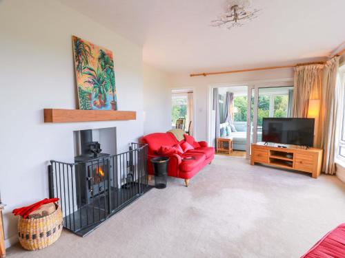 a living room with a red chair and a television at Knockendoch in Dumfries