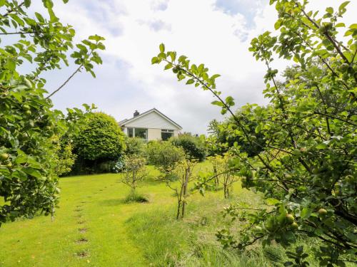 a garden with trees and a house in the background at Knockendoch in Dumfries