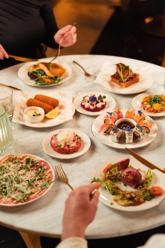 a table full of plates of food with people eating at Van der Valk TheaterHotel De Oranjerie in Roermond