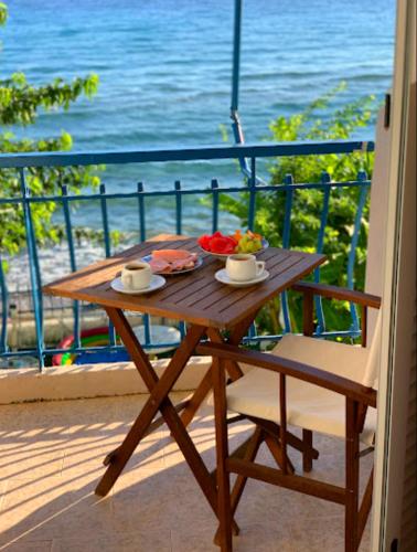 a wooden table with a bowl of fruit on a balcony at Psarou Thalassa Studios in Amoudi