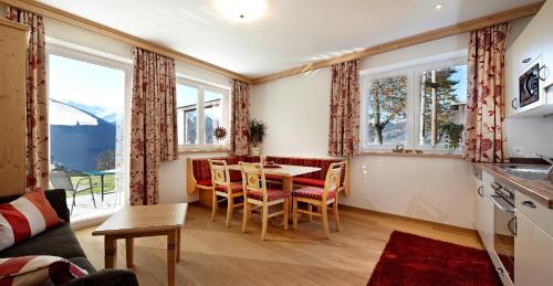 a living room with a table and chairs and windows at Alpenhof Apartments in Mittersill