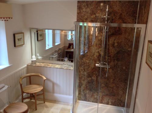 a bathroom with a shower with a chair and a mirror at Gardeners Cottage B and B in Bakewell