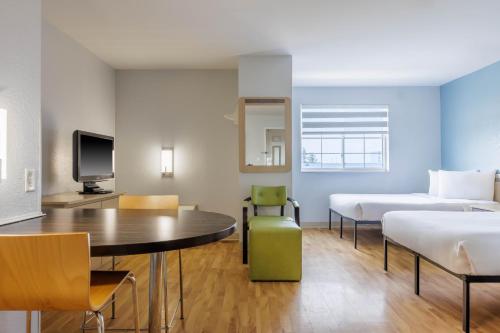 a hotel room with two beds and a table and chairs at Studio 6 Toronto - Mississauga with Kitchenettes in Mississauga