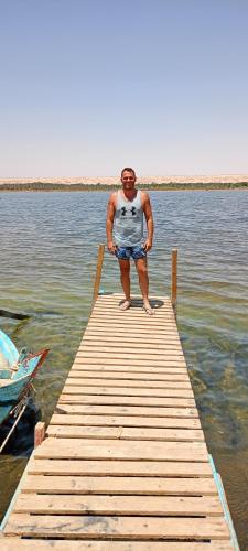 a man standing on a dock in the water at Oasis Panorama Hotel in Bawiti