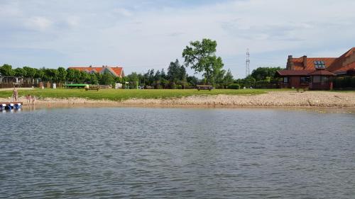 a body of water with a house in the background at Aparthotel EuforiaPort in Pisz