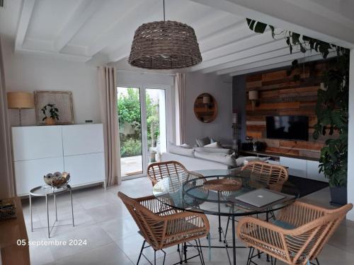 un salon avec une table en verre et des chaises dans l'établissement VILLA DE PLAIN PIED ET STUDIO CLIMATISES , AU CALME , 6 PERSONNES MAXIMUM POUR LE MEME GROUPE, A 7mn DU GOLF ET DE LA PLAGE, à Seignosse