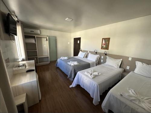 Una habitación de hotel con dos camas y un televisor. en Pousada Casarão Schmidt, en Pomerode