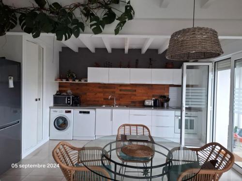 a kitchen with a glass table and chairs in a kitchen at VILLA DE PLAIN PIED ET STUDIO CLIMATISES, AU CALME, 6 PERSONNES MAXIMUM A 7mn DU GOLF ET DE LA PLAGE in Seignosse