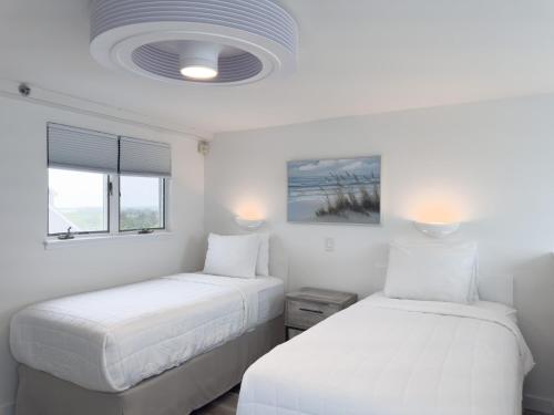 two beds in a room with white walls at Windward Shores in Amagansett