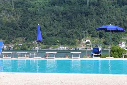 a swimming pool with chairs and tables and an umbrella at Casa Giò in Brusimpiano