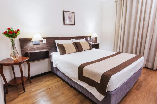 a bedroom with a bed and a vase of flowers on a table at Hotel Golden Park Ribeirão Preto by Nacional Inn in Ribeirão Preto