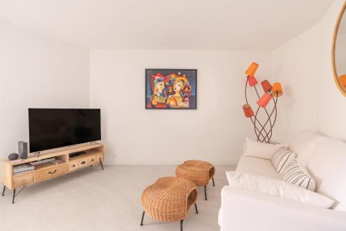 a white living room with a white couch and a tv at Corniche Azur YourHostHelper in Sète