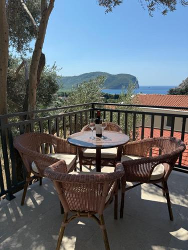 a table and chairs on a balcony with a bottle of wine at Apartmani Krsto in Kravlja