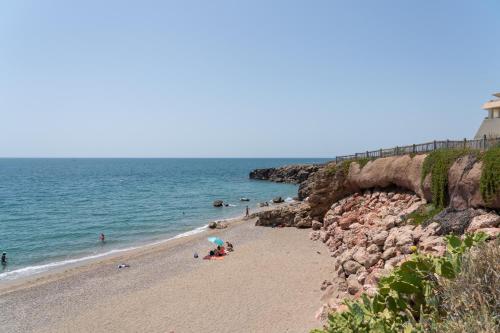 a beach with people sitting on the sand and a lighthouse at Corniche Azur YourHostHelper in Sète