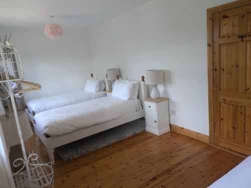 a white bedroom with a bed and a night stand at Danesfort House in Balnacart