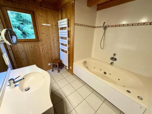 une salle de bain avec une baignoire et un lavabo dans l'établissement Chalet Cristal - Chalet de charme avec sauna et superbe vue sur le MOnt Charvin et les Aravis MAE-1154, à Crest-Voland