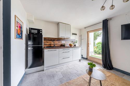 a kitchen with white cabinets and a black refrigerator at Infinity Lovas in Lovas