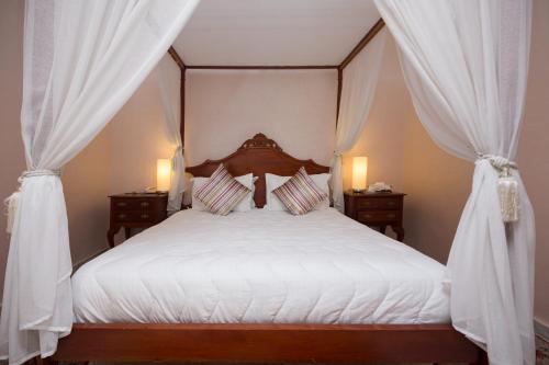 a bedroom with a canopy bed with white curtains at Zalagh Parc Palace in Fès