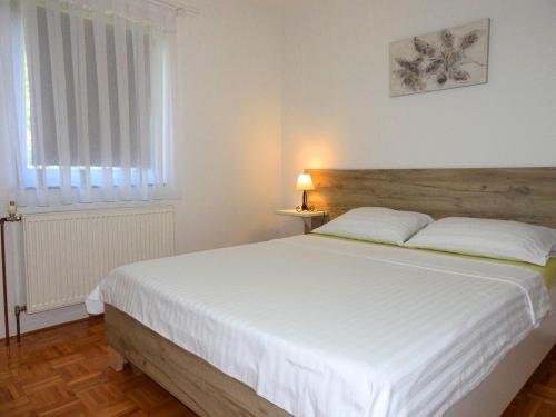 a bedroom with a white bed and a window at Apartment Golden Fields in Smoljanac