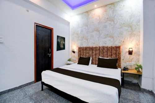 a bedroom with a large bed and a wall at Hotel O VELMORA HOTEL in Lucknow