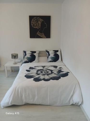 une chambre avec un lit avec une couette noire et blanche dans l'établissement Jolie appartement, à Mulhouse