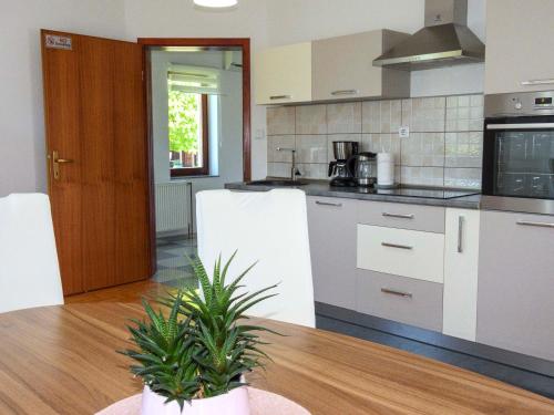 a kitchen with white appliances and a table with a plant at Apartment Golden Fields in Smoljanac