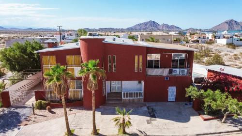 a red house with palm trees in front of it at Hacienda del Desierto in San Felipe