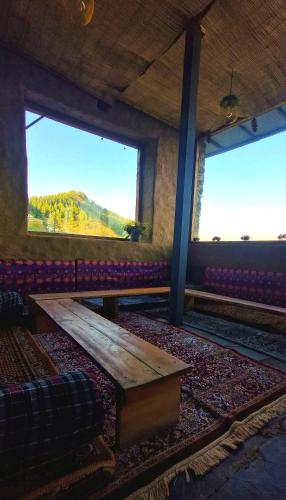 a room with a couch and a table and two windows at The Astro Orchard in Shimla