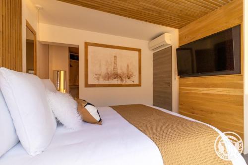 a bedroom with a white bed and a flat screen tv at Casa di Mamma in Trélazé