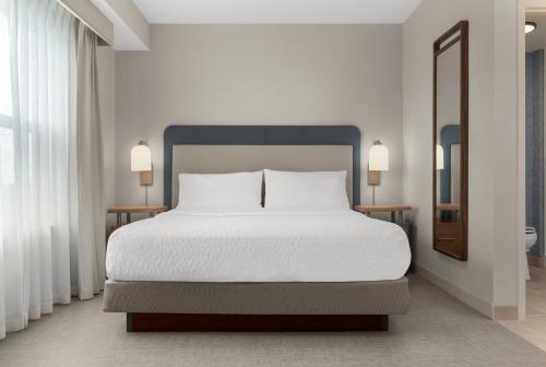 a bedroom with a large bed with white sheets at Homewood Suites by Hilton Burlington in Burlington