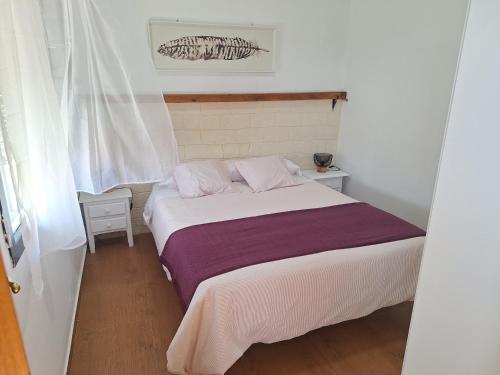 a bedroom with a white bed with purple sheets at Los Duendes in El Puerto de Santa María
