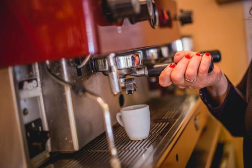 a person making a cup of coffee in a coffee machine at Hotel Raffaello in Bellaria-Igea Marina