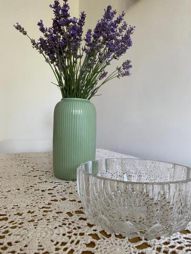 a green vase with purple flowers sitting on a table at Peowiaków Guest Apartment in Zamość