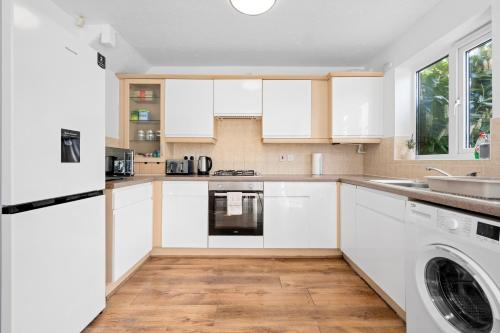 a kitchen with white cabinets and a washer and dryer at 3BDR Gated parking near city centre in Manchester