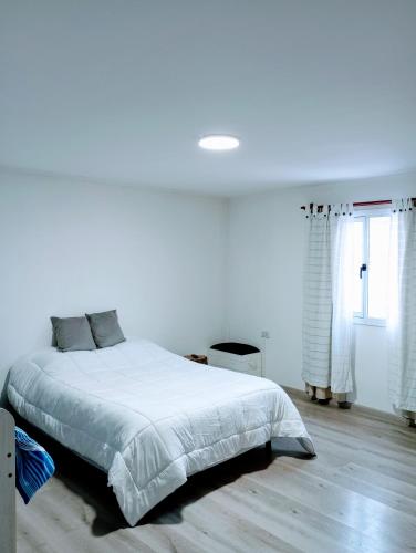 a white bedroom with a large bed and a window at Elal kayak in Comandante Luis Piedra Buena