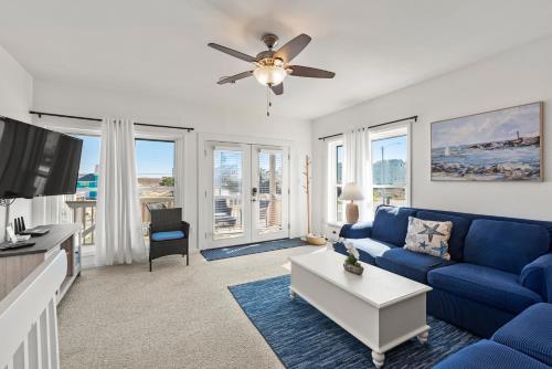a living room with a blue couch and a tv at Sea Escape in Kill Devil Hills