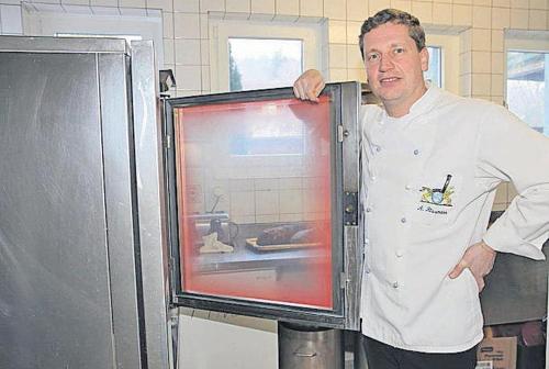 a chef standing in front of a refrigerator at Dorfstrasse 45 Sankt Annen in Sankt Annen