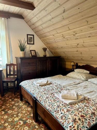 a bedroom with a large bed with a wooden ceiling at Leśne PoBudki in Białowieża