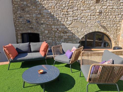 a patio with chairs and a couch and a table at Charmante maison provençale proche d'Uzès in Garrigues-et-Sainte-Eulalie