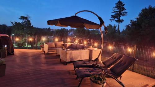 a patio with couches and an umbrella and lights at Pratum Plus prywatny ogród z tarasem grill leżaki in Mikołajki