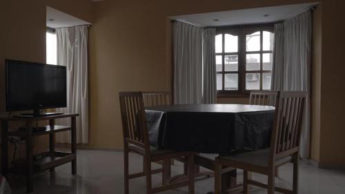 a dining room with a table and chairs and a television at Cabañas María CAROLINA in San Luis