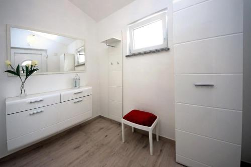 un bagno con mobili bianchi e una sedia rossa di Villa Sara a Vodice