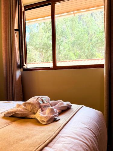 a towel sitting on a bed in front of a window at Andenes del Inca Hotel in Ollantaytambo